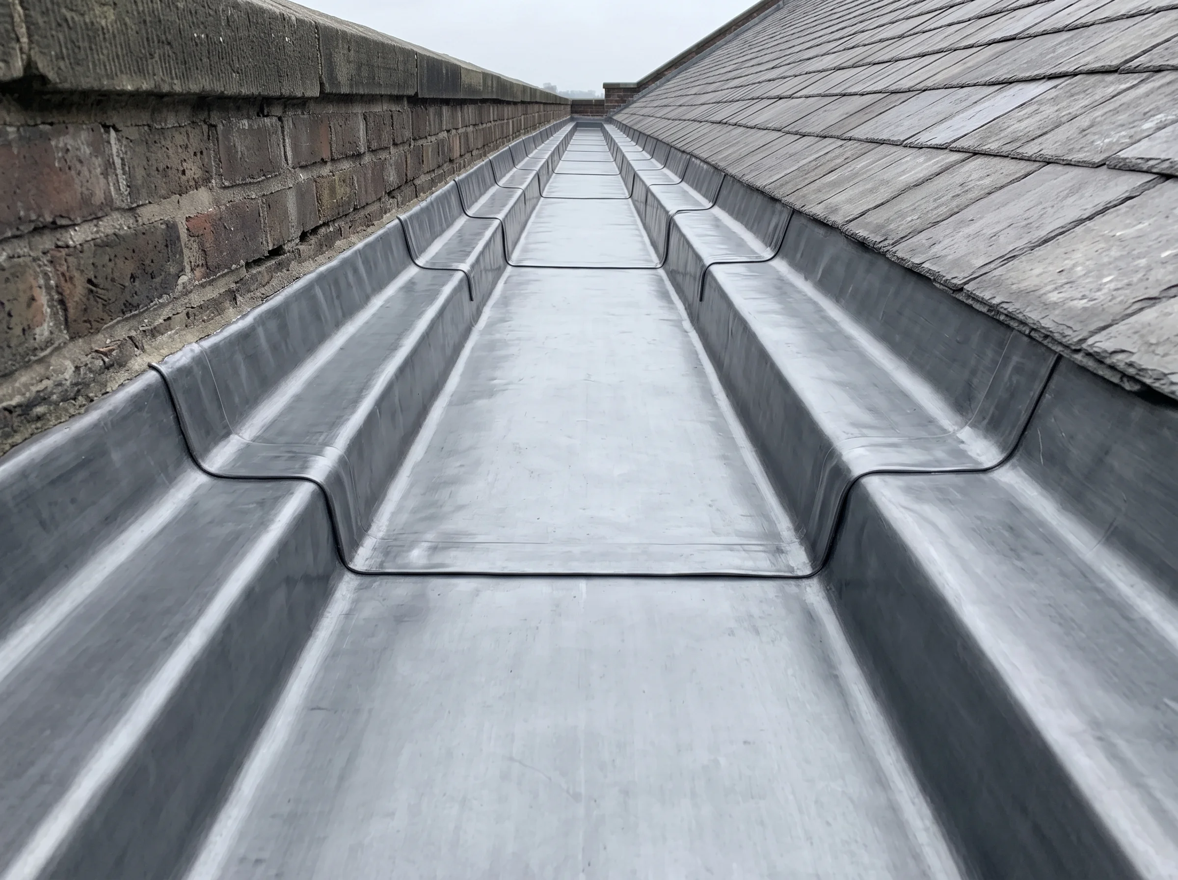 A newly lead-lined parapet gutter running the length of a school roof